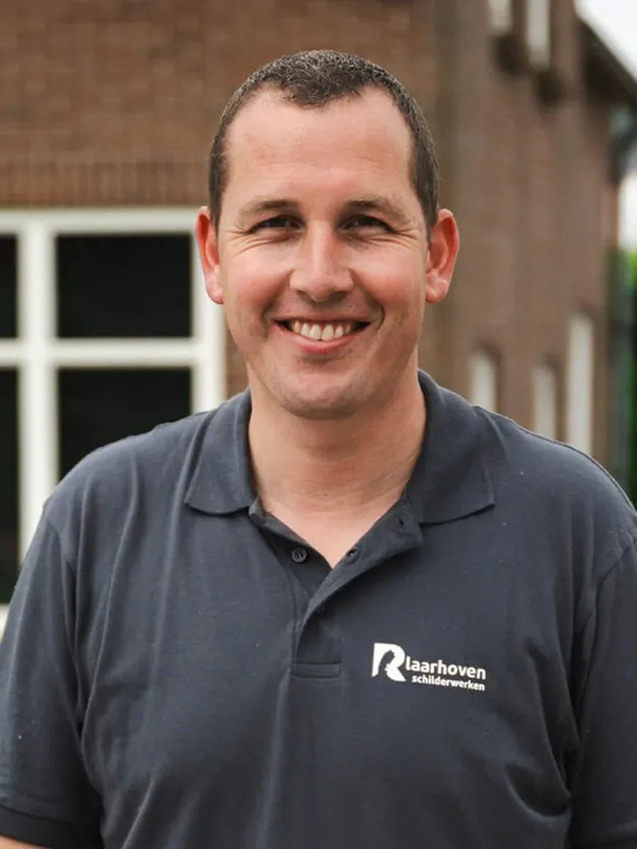 De schilder van Laarhoven Schilderwerken, in bedrijfskleding voor zijn werkplaats